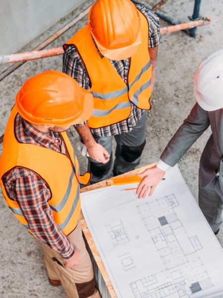 High angle view of builders and architect discussing blueprint at construction site