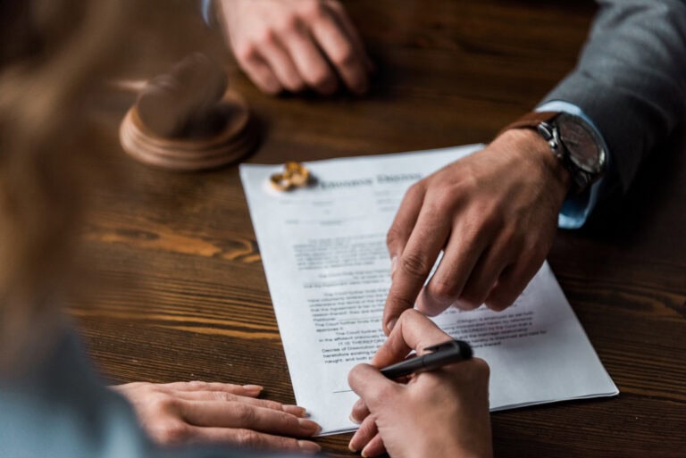 Partial view of judge pointing at papers and client signing divorce decree