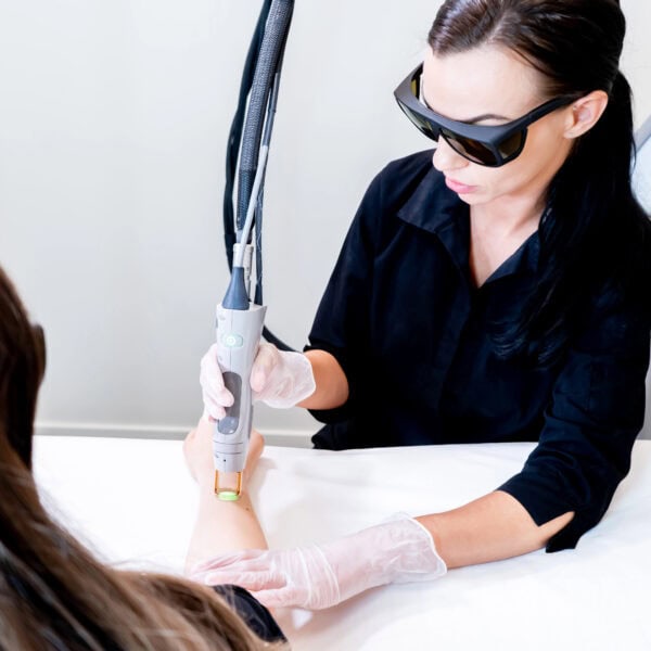 Laser hair removal session with beauty technician and female patient, epilating arm hair, in a cosmetology skin clinic.