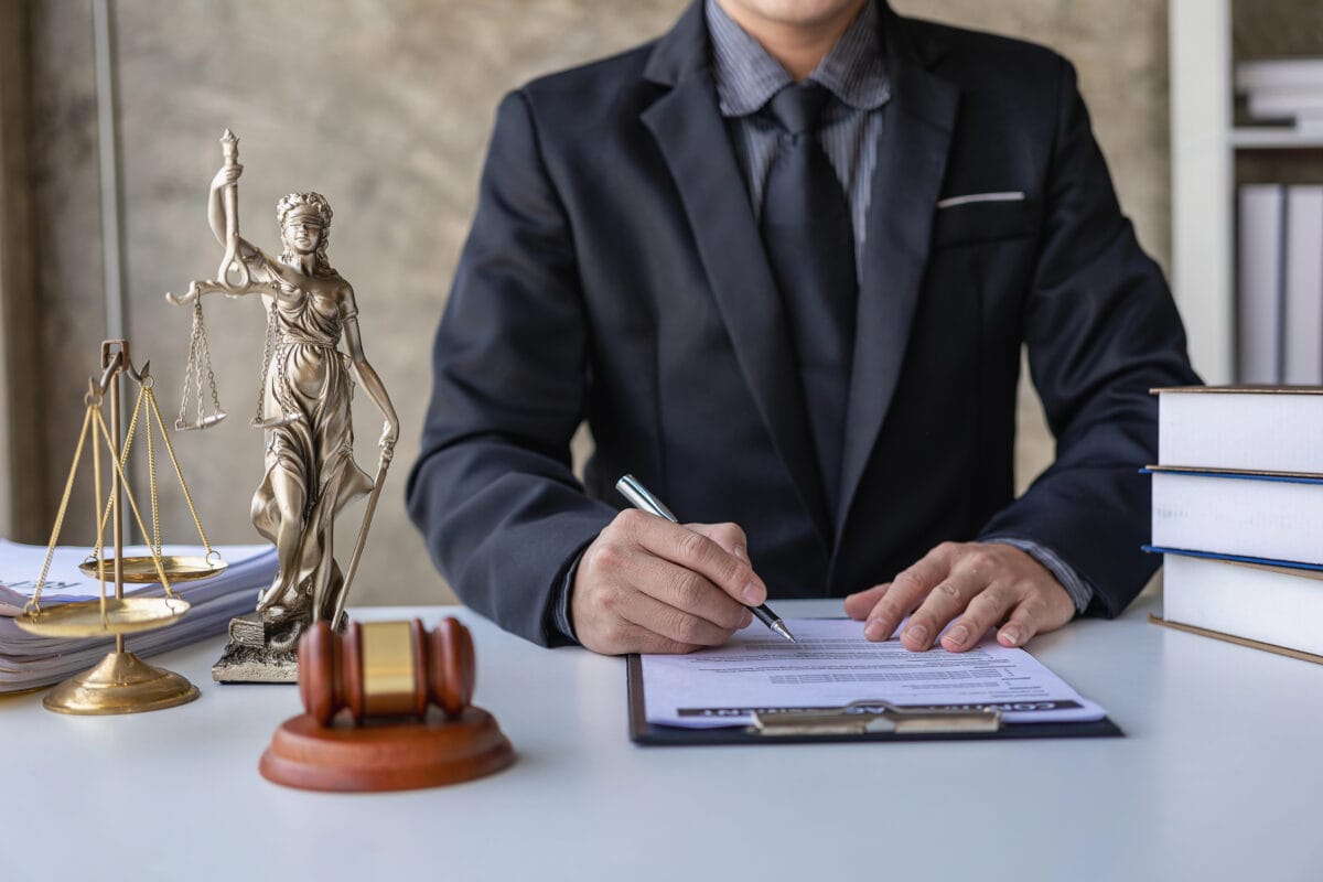 Asian male lawyer working in a law office with a judge's gavel and a weight scale on the table, legal consulting concept.